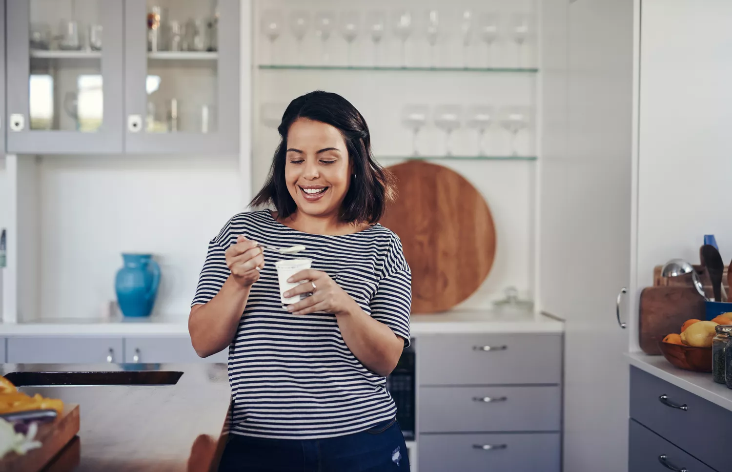 Young woman eating yogurt in kitchen