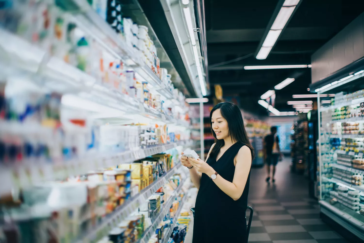 Woman looking at product's nutrition label in a grocery store aisle