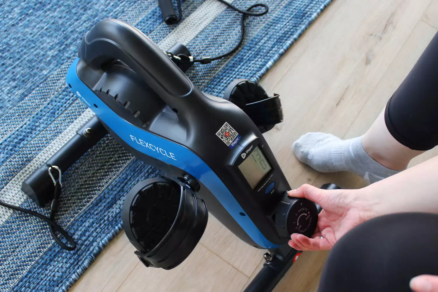 Person turning a dial on the LifePro FlexCycle Under Desk Bike Pedal Exerciser