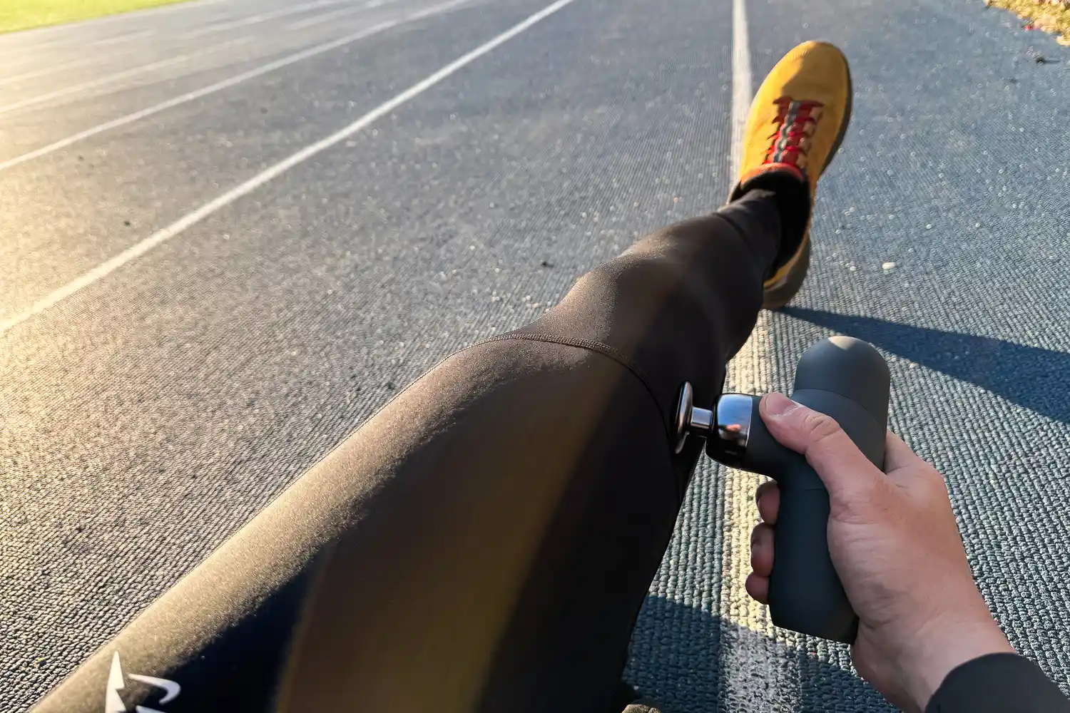 A person uses the Renpho Mini Thermal Massage Gun on their leg